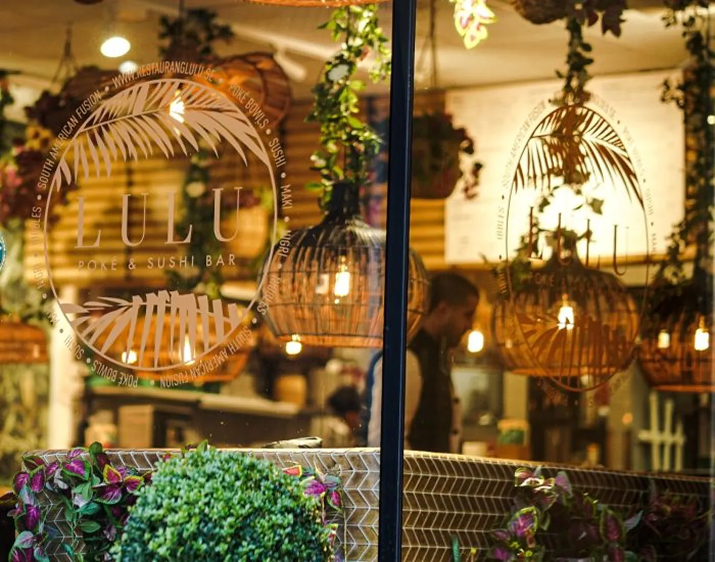 Restaurang Lulus skyltfönster, med logotypen på glaset och hängande rottinglampor innanför